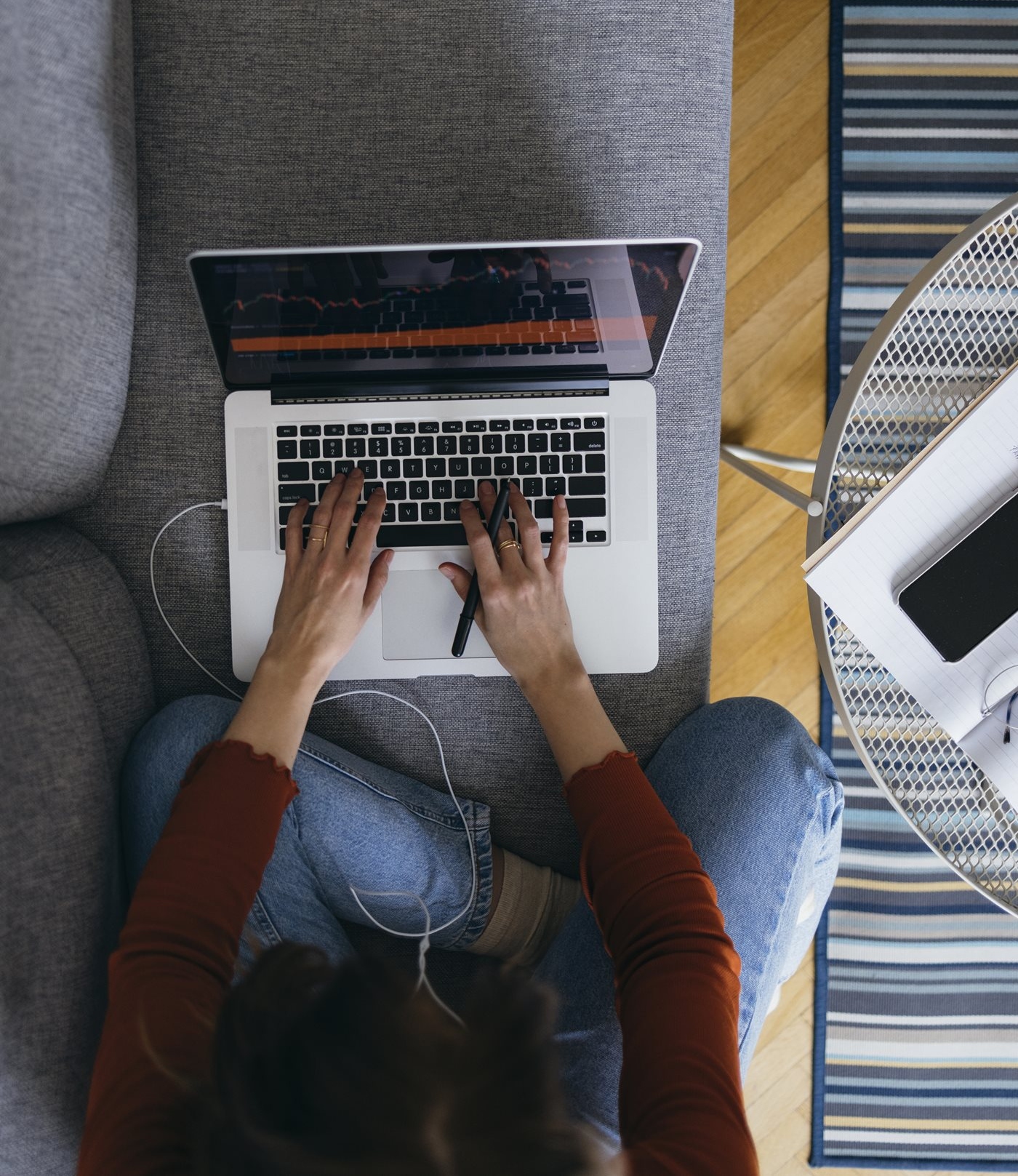 Mujer escribiendo en una computadora portátil mientras está sentada con las piernas cruzadas en el sofá