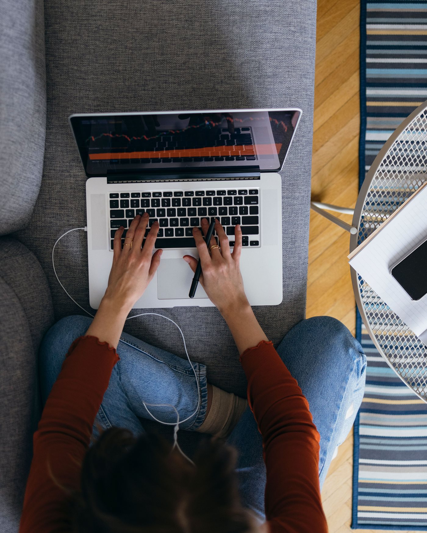 Woman typing on laptop while sitting cross legged on couch